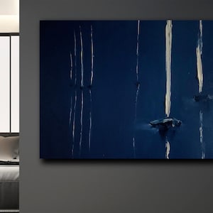Könnte beinhalten: Abstrakte Ölgemälde auf Leinwand. Das Kunstwerk zeigt einen tiefblauen Hintergrund mit vertikalen weißen und cremeweißen Pinselstrichen. Das Gemälde hat ein strukturiertes Aussehen und ist an einer dunkelgrauen Wand befestigt.