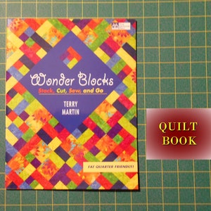May include: A colorful book titled "Wonder Blocks: Stack, Cut, Sew, and Go" by Terry Martin. The book cover features a patchwork design with a blue background and the text "Fat Quarter Friendly!" at the bottom. The book is labeled as a "Quilt Book".