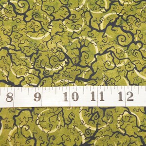May include: Green fabric with a black and white swirling pattern. The fabric is measured with a ruler showing 7 to 13 inches.