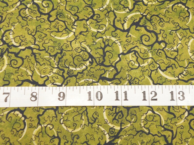 May include: Green fabric with a black and white swirling pattern. The fabric is measured with a ruler showing 7 to 13 inches.
