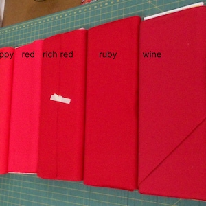 May include: Five fabric swatches in different shades of red, labeled "poppy", "red", "rich red", "ruby", and "wine".