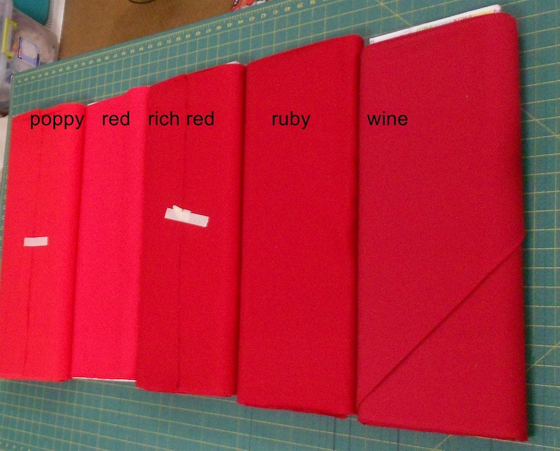May include: Five fabric swatches in different shades of red, labeled "poppy", "red", "rich red", "ruby", and "wine".