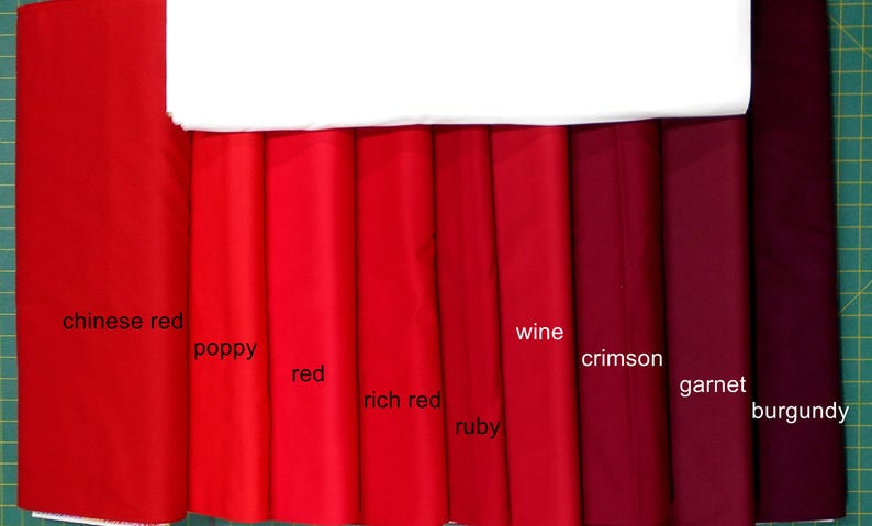 May include: A swatch card of ten different shades of red fabric, from light to dark. The swatches are labeled with the names "Chinese Red", "Poppy", "Red", "Rich Red", "Ruby", "Wine", "Crimson", "Garnet", and "Burgundy".