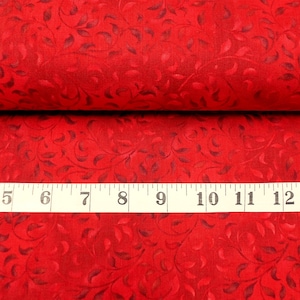 May include: Red fabric with a dark red leaf pattern. A white measuring tape with black markings reads "4, 5, 6, 7, 8, 9, 10, 11, 12, 13" and "CHINA" is printed on the tape.