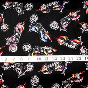 May include: Black fabric with a repeating pattern of chrome motorcycles with flames. The motorcycles are in various shades of red, orange, yellow, blue, and purple.