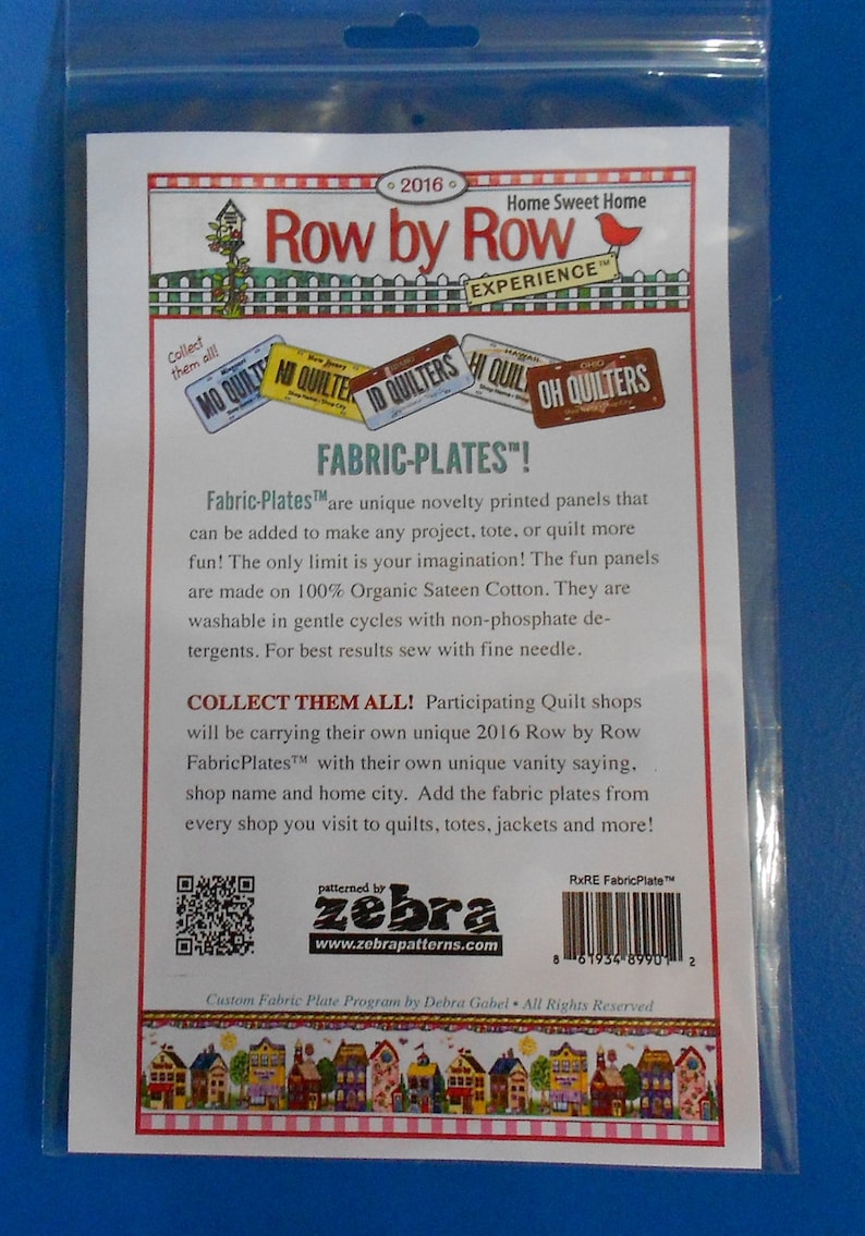 May include: A white card with a colorful illustration of houses and a red bird. The text "Row by Row Experience" is printed in black. The text "Fabric-Plates!" is printed in black. The text "Collect them all!" is printed in black. The text "Participating Quilt shops will be carrying their own unique 2016 Row by Row FabricPlates&trade; with their own unique vanity saying. shop name and home city. Add the fabric plates from every shop you visit to quilts, totes, jackets and more!" is printed in black. The text "Custom Fabric Plate Program by Debra Gabel All Rights Reserved" is printed in black. The text "patterned by zebra www.zebrapatterns.com" is printed in black. The text "RxRE FabricPlate&trade;" is printed in black. A barcode is printed in black.