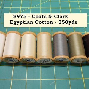 May include: Seven spools of Coats & Clark Egyptian Cotton thread in various neutral colors, including white, cream, and brown. The spools are arranged on a green grid surface. Text on the image reads "S975 - Coats & Clark Egyptian Cotton - 350yds."