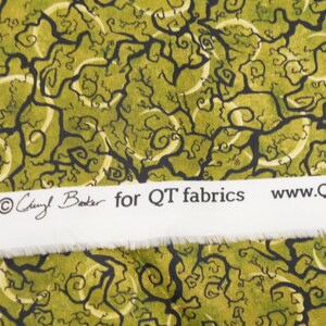 May include: Green fabric with a black and white swirling tree pattern. The fabric has a white label with the text "Cheryl Baker for QT fabrics www.QTfabrics.com".