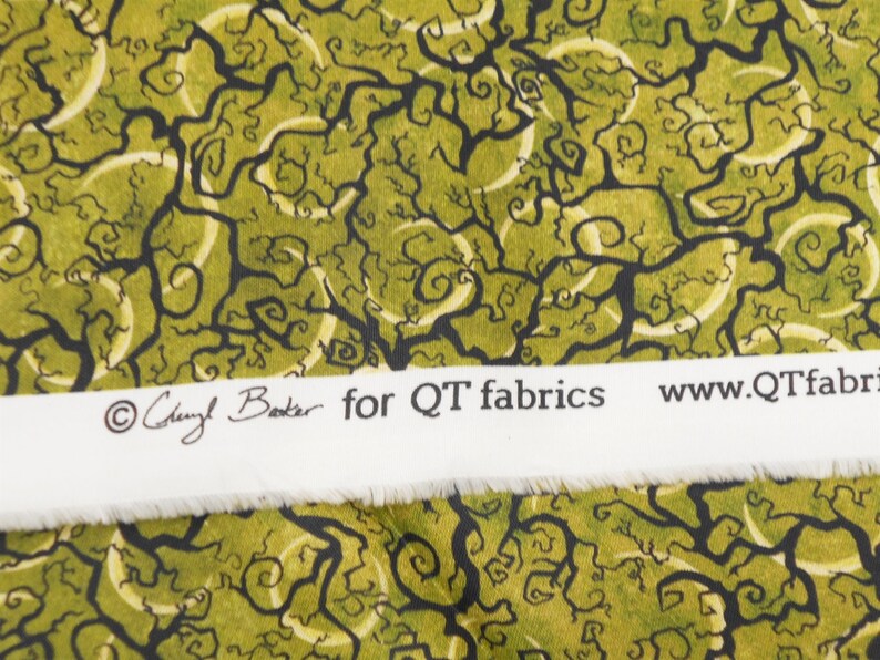 May include: Green fabric with a black and white swirling tree pattern. The fabric has a white label with the text "Cheryl Baker for QT fabrics www.QTfabrics.com".