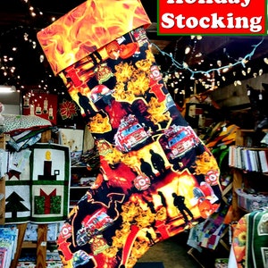 May include: A red and black Christmas stocking with a fire engine and firefighter theme. The stocking has a bright orange cuff with flames printed on it. The text "Holiday Stocking" is printed in white on a green background.
