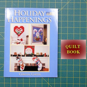 May include: A blue book titled "Holiday Happenings" with a picture of a fireplace with stockings, a Santa Claus, and a bunny rabbit on the cover. The book is labeled "Quilt Book".