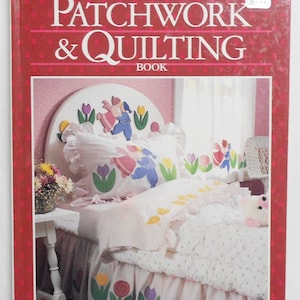 May include: A book cover for "New Patchwork & Quilting Book" by Better Homes and Gardens. The cover features a pink and white bedroom with a bed featuring a patchwork quilt with a floral design.