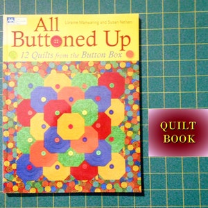 May include: A book titled "All Buttoned Up" with a colorful quilt design on the cover. The book is a quilting guide with 12 quilt patterns. The text on the cover reads "12 Quilts from the Button Box".