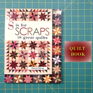 May include: A book titled "S is for SCRAPS 18 great quilts" by Gayle Bong. The cover features a patchwork quilt design with a variety of colors and patterns. The book is labeled "QUILT BOOK" on a red background.