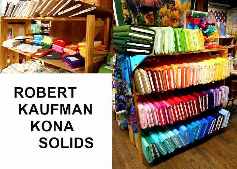 May include: A shelf display of Robert Kaufman Kona Solids fabric in a variety of colors. The fabric is arranged in rows by color, starting with green and ending with blue.
