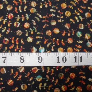 May include: Black fabric with a repeating pattern of small, colorful circles and stylized dragonfly shapes. A white measuring tape with black markings reads 6 to 12 inches.