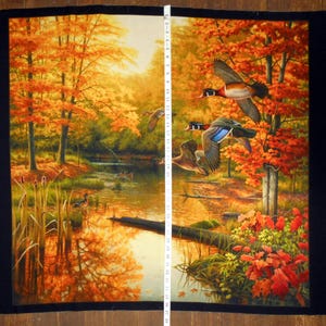 May include: A fabric panel with a woodland scene featuring a stream, trees with orange and yellow leaves, and a flock of wood ducks in flight.