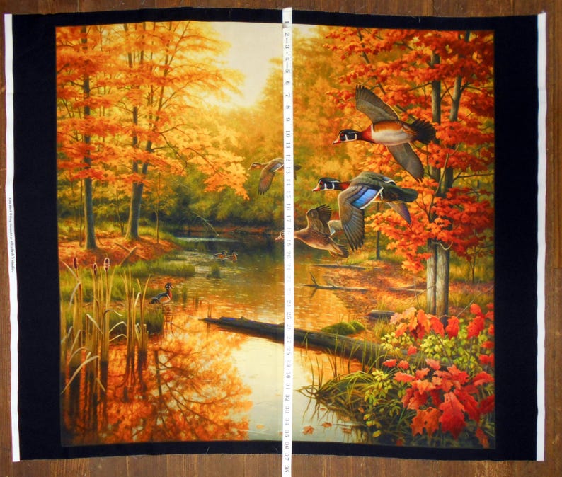 May include: A fabric panel with a woodland scene featuring a stream, trees with orange and yellow leaves, and a flock of wood ducks in flight.