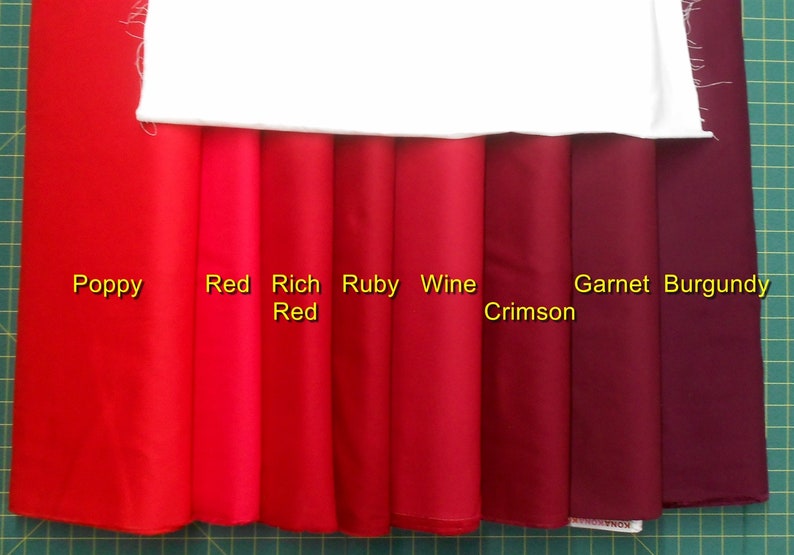 May include: Eight fabric swatches in shades of red, from bright poppy red to deep burgundy. The swatches are labeled "Poppy", "Red", "Rich Red", "Ruby", "Wine Crimson", "Garnet", and "Burgundy".