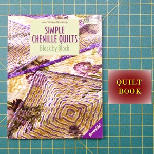 May include: A book titled "Simple Chenille Quilts: Block by Block" by Amy Whalen Helmcamp. The book cover features a close-up of a colorful chenille quilt with a floral pattern. The book is labeled "Reversible" and is a quilt book.