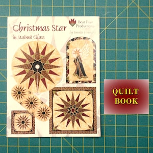 May include: A quilt book titled "Christmas Star in Stained Glass" by Brenda Henninger. The book cover features a colorful stained glass star design with red, gold, and brown hues. The book is published by Bear Paw Productions.