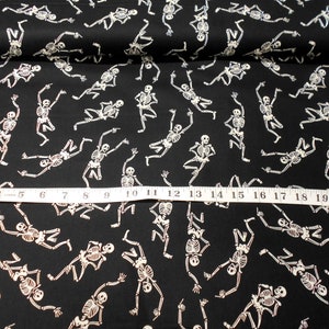Peut inclure: Tissu noir avec un motif de squelettes blancs. Les squelettes dansent et ont un aspect amusant et fantaisiste. Le tissu est parfait pour les projets et les travaux manuels d'Halloween.