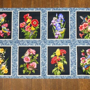 May include: A blue and white fabric with a repeating pattern of birds and flowers in a variety of colors. Each bird and flower is framed in a black square with a blue and white border.