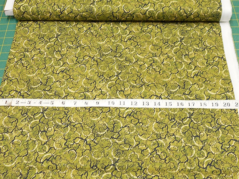 May include: Green fabric with a swirling, abstract pattern. The fabric has a textured surface and is approximately 20 inches wide.