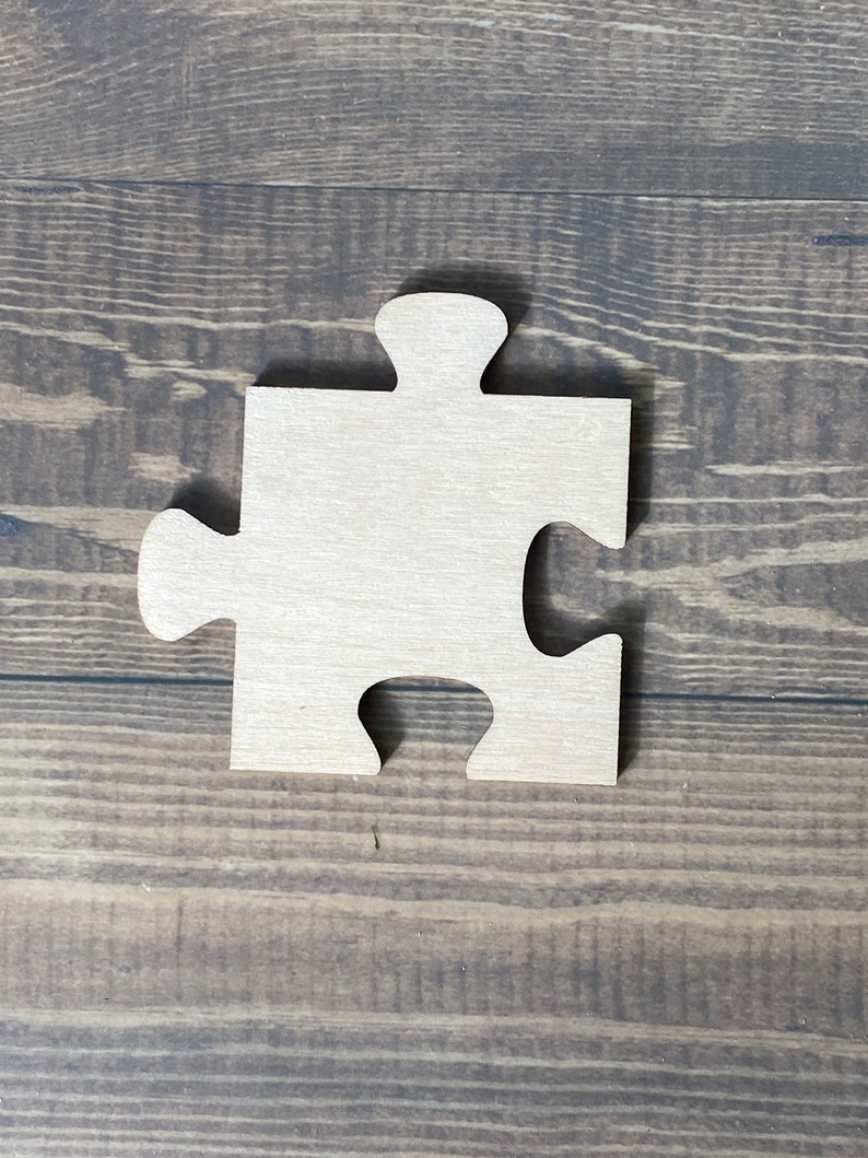 Peut inclure: Une pi&egrave;ce de puzzle en bois en forme de pi&egrave;ce de puzzle. La pi&egrave;ce est de couleur brun clair et a une surface lisse.