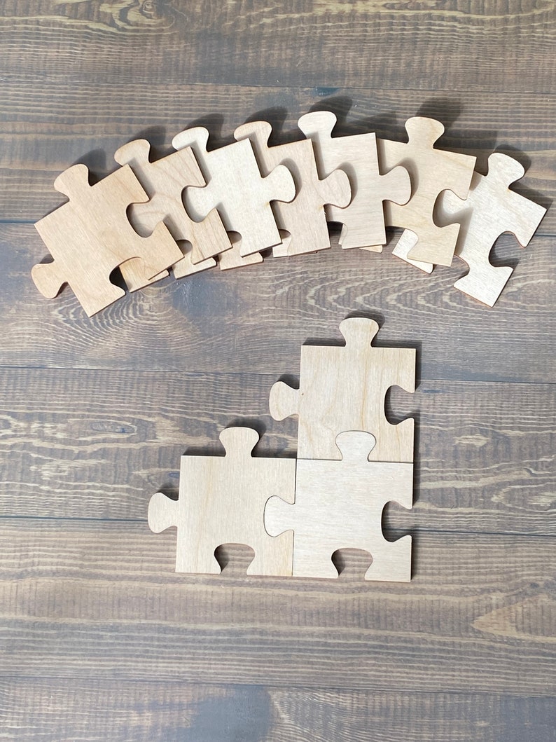 Peut inclure: Un ensemble de pi&egrave;ces de puzzle en bois en forme de puzzle. Les pi&egrave;ces sont dispos&eacute;es en ligne courbe en haut de l'image, et deux pi&egrave;ces sont assembl&eacute;es en bas de l'image.
