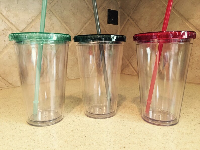 May include: Three clear plastic tumblers with lids and straws. The lids are green, red, and green. The straws are green, gray, and red.
