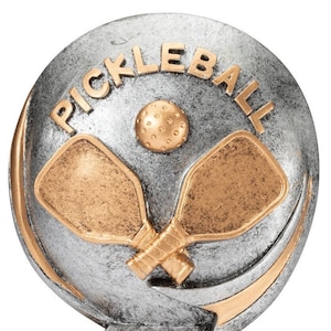 May include: Silver and gold pickleball trophy with two crossed paddles and a ball on a round base. The base is inscribed with the word "Pickleball".