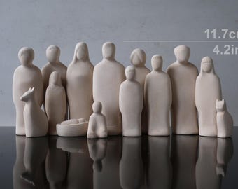 May include: A collection of twelve light beige, smooth, abstract wooden figurines representing people and animals, including a small cradle. The tallest figures measure 4.2 inches in height. The set features minimalist, featureless human shapes.