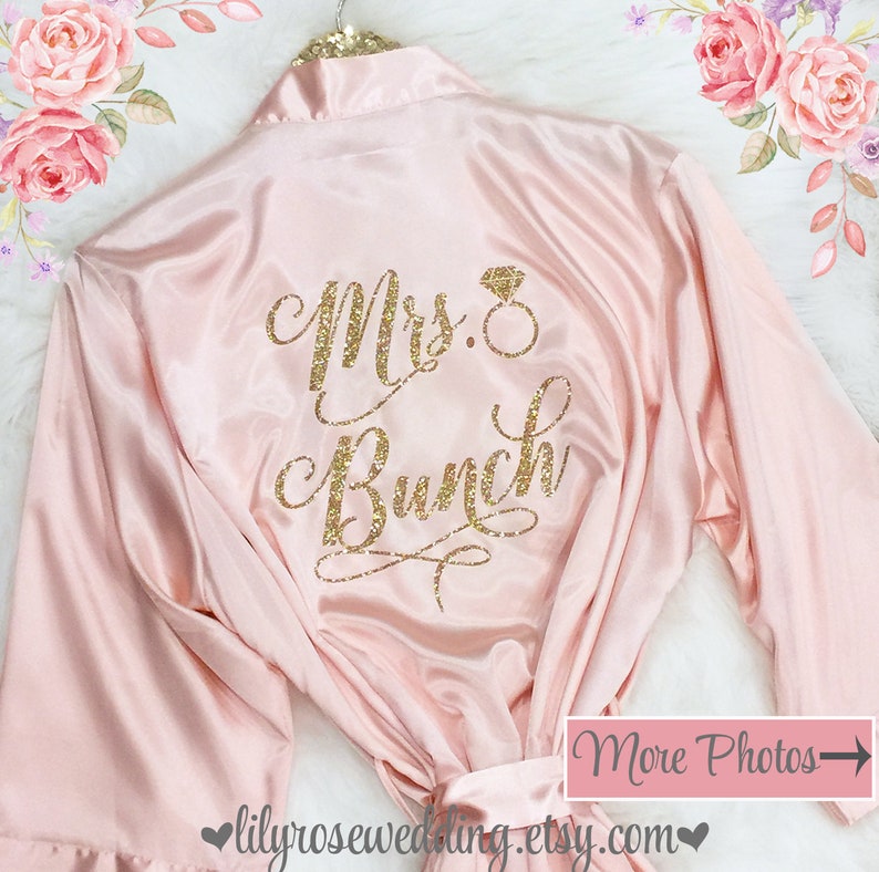 May include: A pink satin robe with a gold glitter design that says "Mrs. Bunch" with a ring symbol.