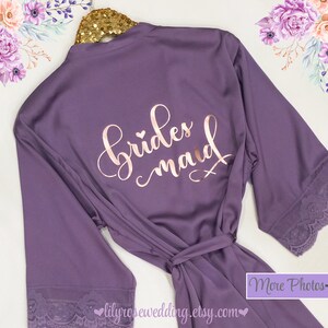 May include: Purple satin robe with lace trim and the words "bridesmaid" in rose gold lettering.