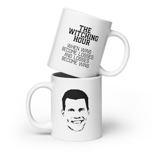 May include: White ceramic mug with a black silhouette of a man's face and the text "The Witching Hour When wins become losses, and losses become wins".