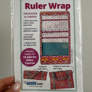 May include: A Ruler Wrap organizer and carrier pattern package by Annie.com. The packaging features a red and pink floral fabric design, showing the wrap unfolded with pockets, and folded in two configurations to hold rulers or a cutting mat.
