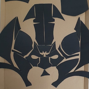 May include: Black paper craft template for a mask with a geometric design. The mask has a pointed top and a wide, flat bottom. The mask is made up of several pieces that are cut out and assembled.