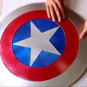 May include: A large, round, silver-colored shield with a red, white, and blue star design. The shield is painted with a red outer ring, a blue inner ring, and a white star in the center.