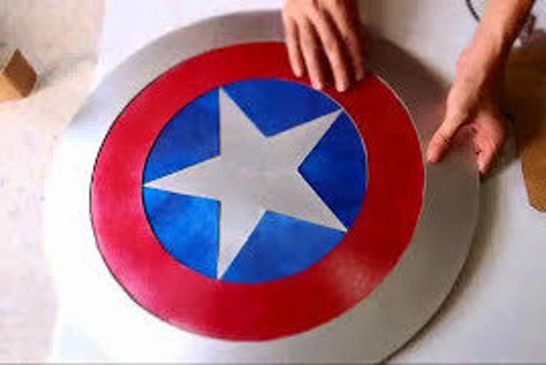 May include: A large, round, silver-colored shield with a red, white, and blue star design. The shield is painted with a red outer ring, a blue inner ring, and a white star in the center.