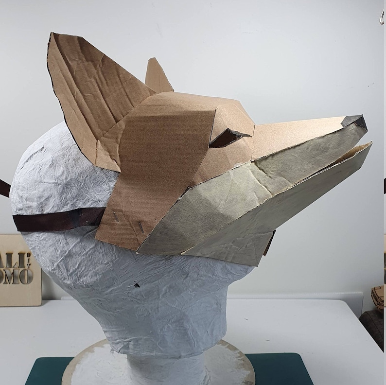 Pode incluir: Uma m&aacute;scara de raposa de cart&atilde;o feita de papel castanho e bege. A m&aacute;scara est&aacute; presa a uma cabe&ccedil;a de manequim branca.