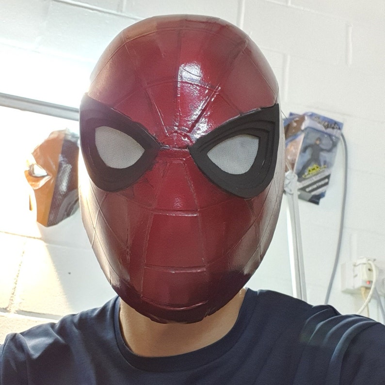 May include: A red and black Spider-Man mask with a black eye mask and a red and black web design.