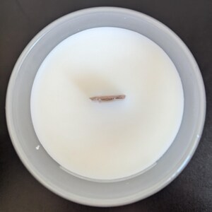 May include: A white candle in a clear glass jar with a wooden wick. The candle is unlit and the wick is visible.