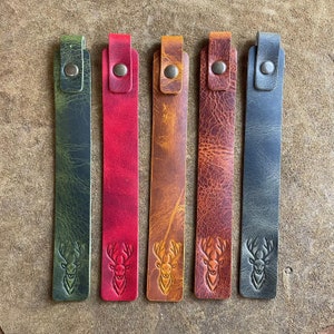 K&ouml;nnte beinhalten: F&uuml;nf Leder-Lesezeichen mit einem Hirschkopf-Design. Die Lesezeichen sind in Gr&uuml;n, Rot, Braun, Braun und Blau.