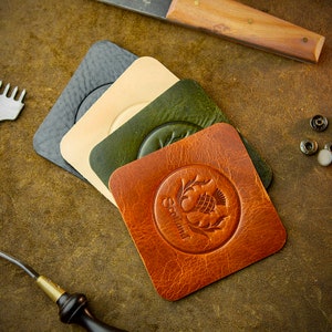 May include: Four leather squares in black, beige, green, and brown. The brown square has an embossed design of a thistle with the word "Scotland" around it.