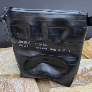 May include: Black zippered pouch made from a recycled bicycle inner tube. The pouch has a Continental brand label with the text "MTB 27.5 47/60-584 made in China 14037111 40 4".