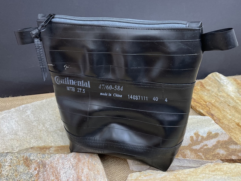 May include: Black zippered pouch made from a recycled bicycle inner tube. The pouch has a Continental brand label with the text "MTB 27.5 47/60-584 made in China 14037111 40 4".