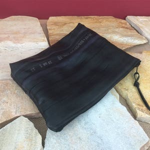 May include: Black zippered pouch made from recycled inner tubes. The pouch has a small loop handle and the text "20/97-559/597(26)(No. 30 10 04 3 13" is visible on the front.