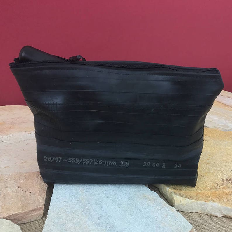 May include: Black zippered pouch made from recycled tire inner tubes. The pouch has a label that reads "28/47 - 559/597/267/No. 17".