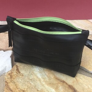May include: Black zippered pouch made from recycled tire inner tubes with a green zipper and a black strap with the text "WALL 40.62" printed on it.